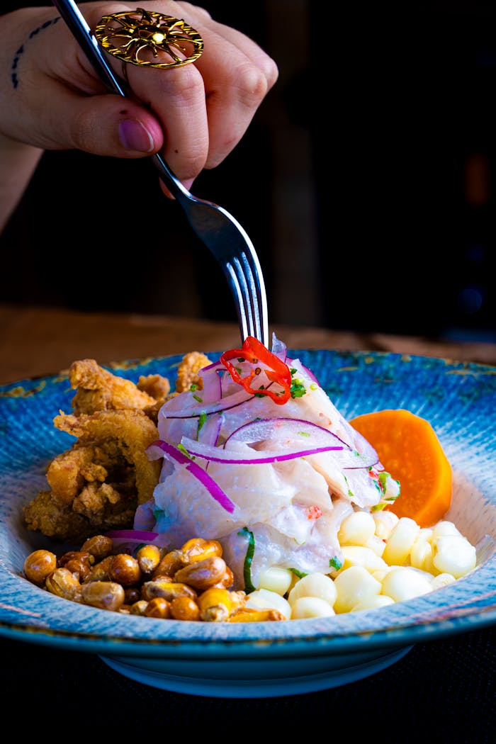 A colorful plate of Peruvian ceviche garnished with fried seafood and corn.